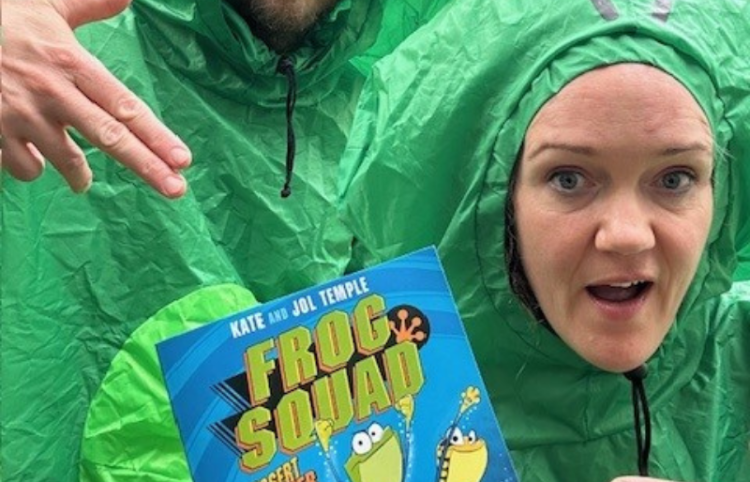 Authors Kate and Jol Temple in green suits with book Frog Squad