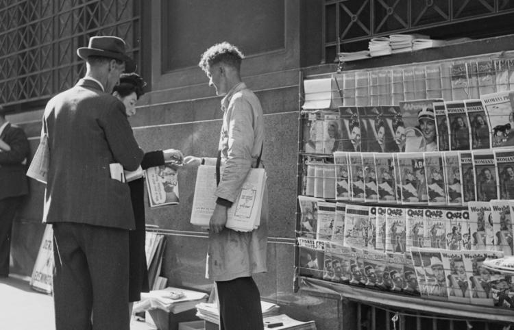two men standing at the newspaper stand