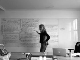 Black and white photograph of woman at whiteboard