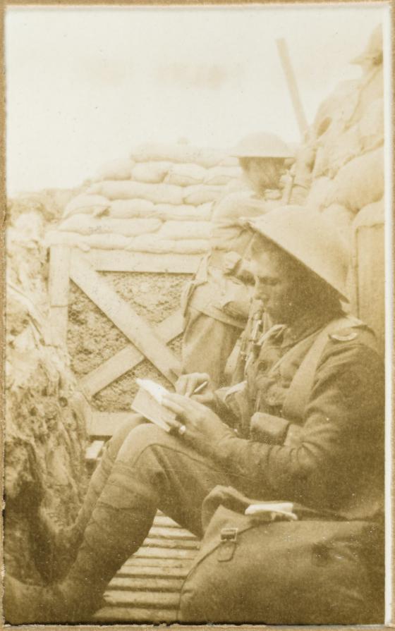 A solider sits in a trench rolling a cigarette 