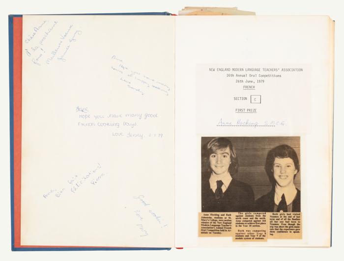 Book page with salutations written inside and a newspaper clipping showing two girs