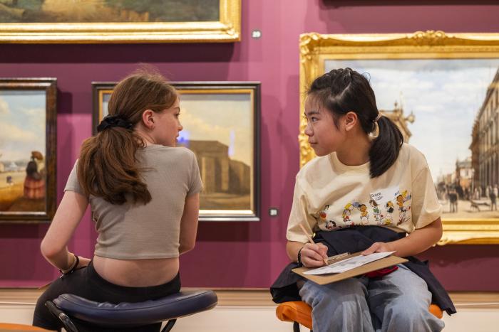 two little girls talking with drawing boards in paintings gallery red room