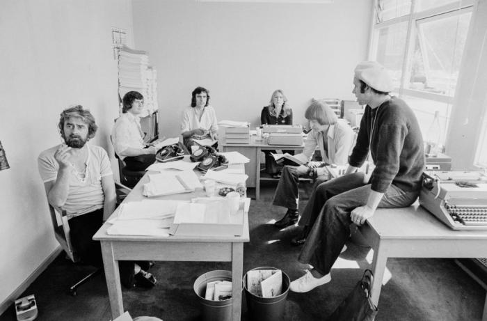 Black and white photograph of people around a desk